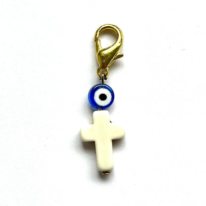 Howlite Cross charm with blue evil eye and gold clasp on white background