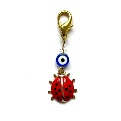Red ladybug good luck charm with a blue evil eye on a white background