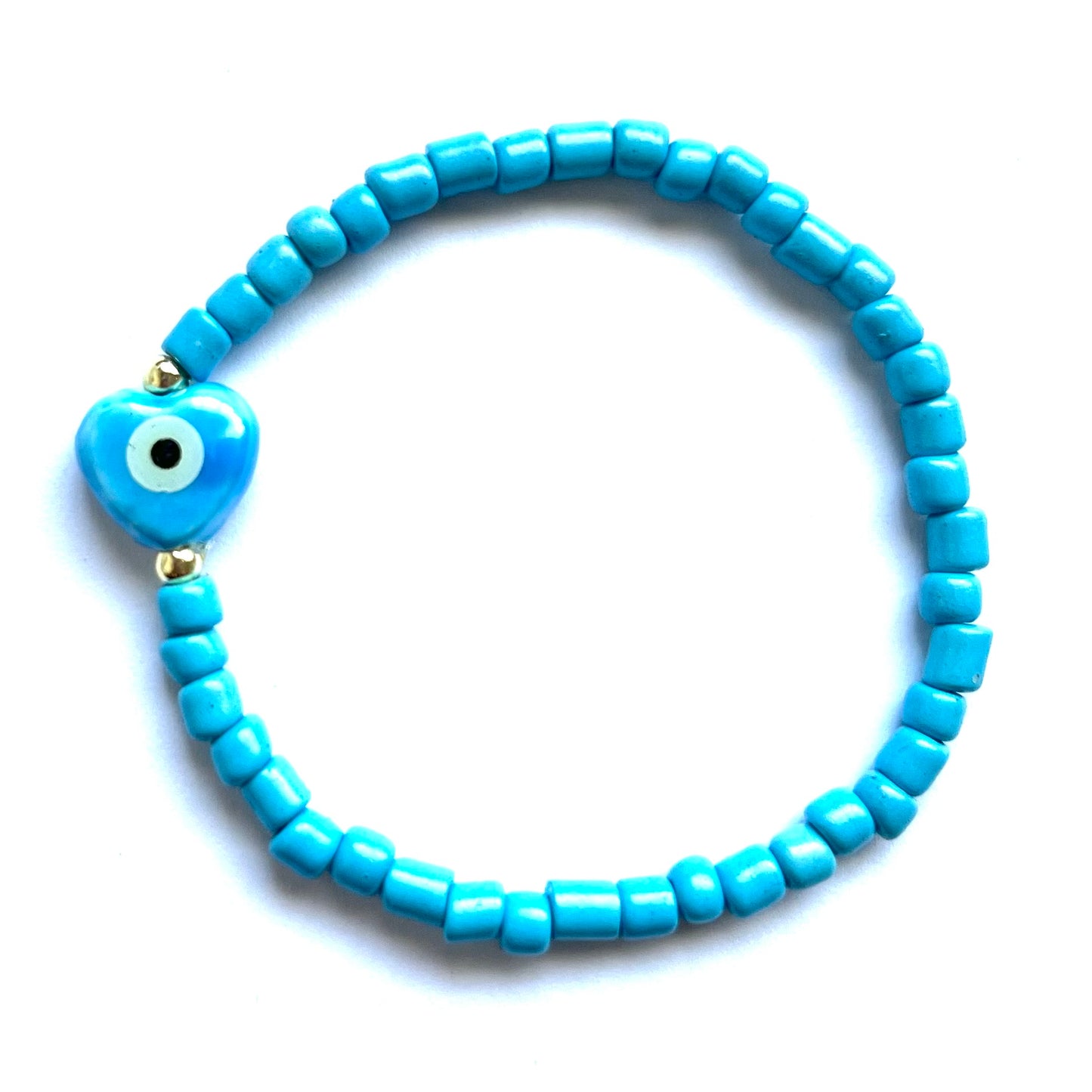 Mykonos mati stackable bracelets with ceramic evil eye charms. Blue beaded bracelet with a heart evil eye charm on a white background
