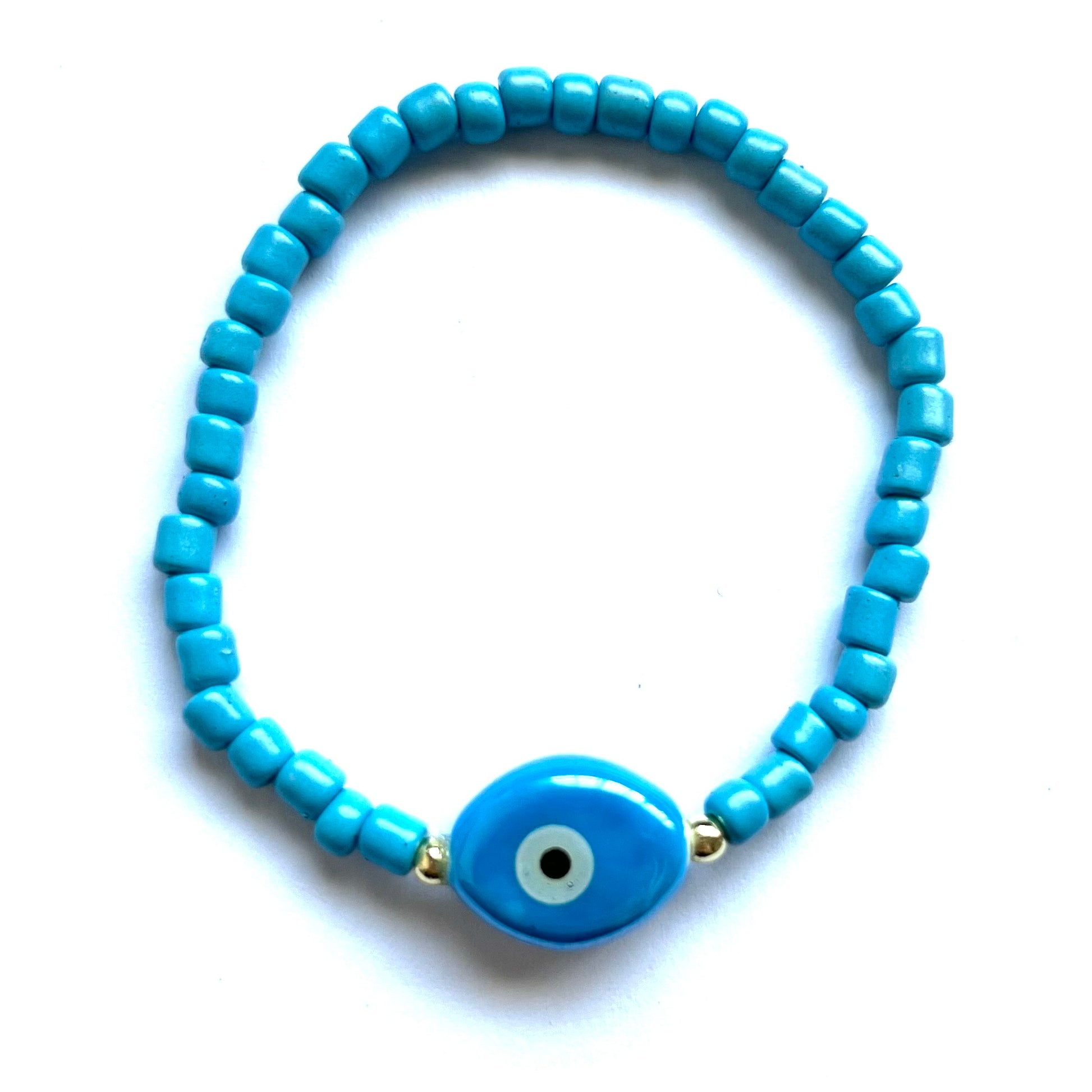 Mykonos mati stackable bracelets with ceramic evil eye charms. Blue beaded bracelet with an oval evil eye charm on a white background
