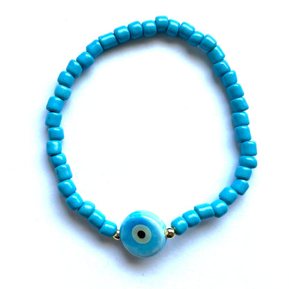 Mykonos mati stackable bracelets with ceramic evil eye charms. Blue beaded bracelet with a square evil eye charm on a white background