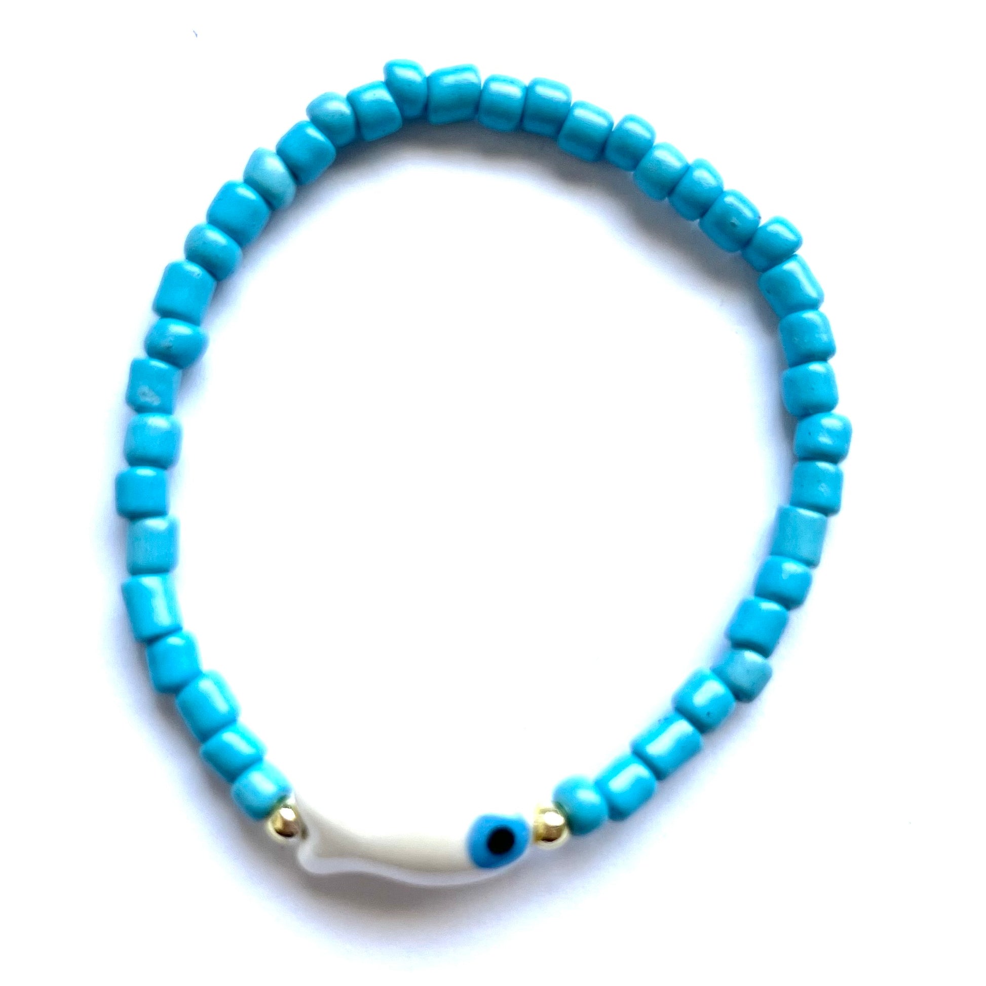Mykonos mati stackable bracelets with ceramic evil eye charms. White beaded bracelet with a fish evil eye charm on a white background