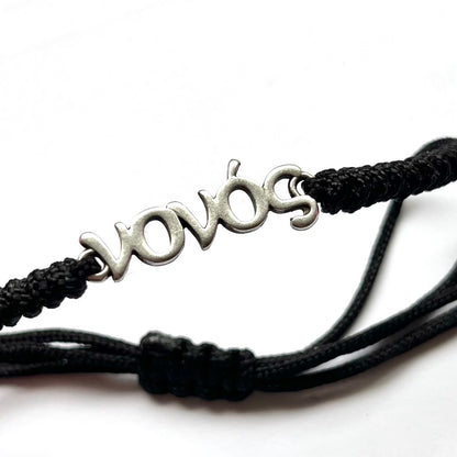 Black braided bracelet with a silver 'vovóς' charm on a white background