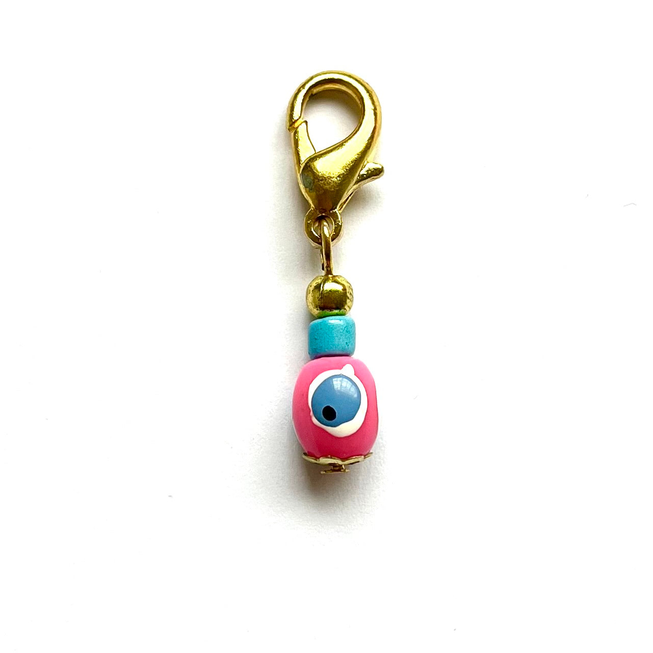 Pink Evil Eye with gold clasp on a white background