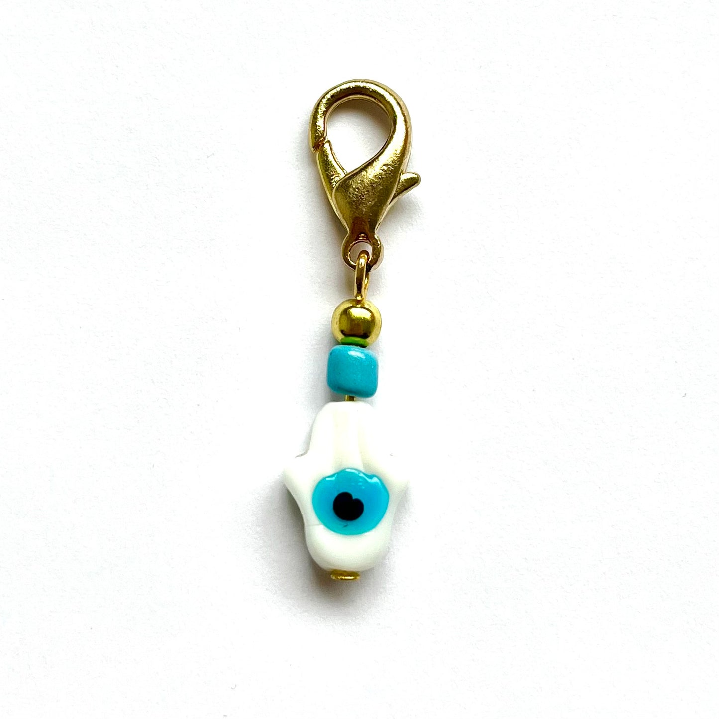 White Hamsa with Evil Eye with blue evil eye and gold clasp on a white background