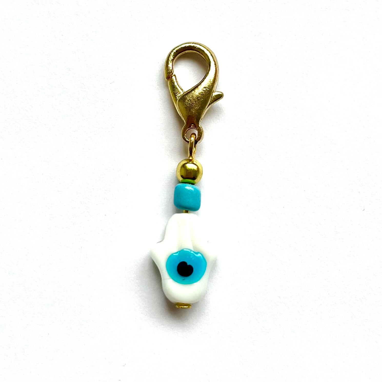 White Hamsa with Evil Eye with blue evil eye and gold clasp on a white background