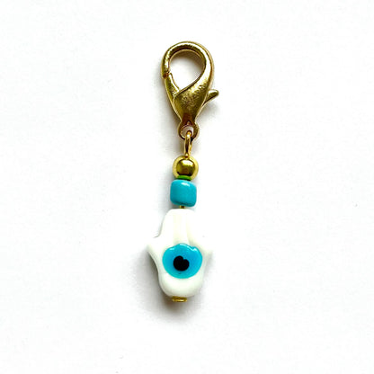 White Hamsa with Evil Eye with blue evil eye and gold clasp on a white background